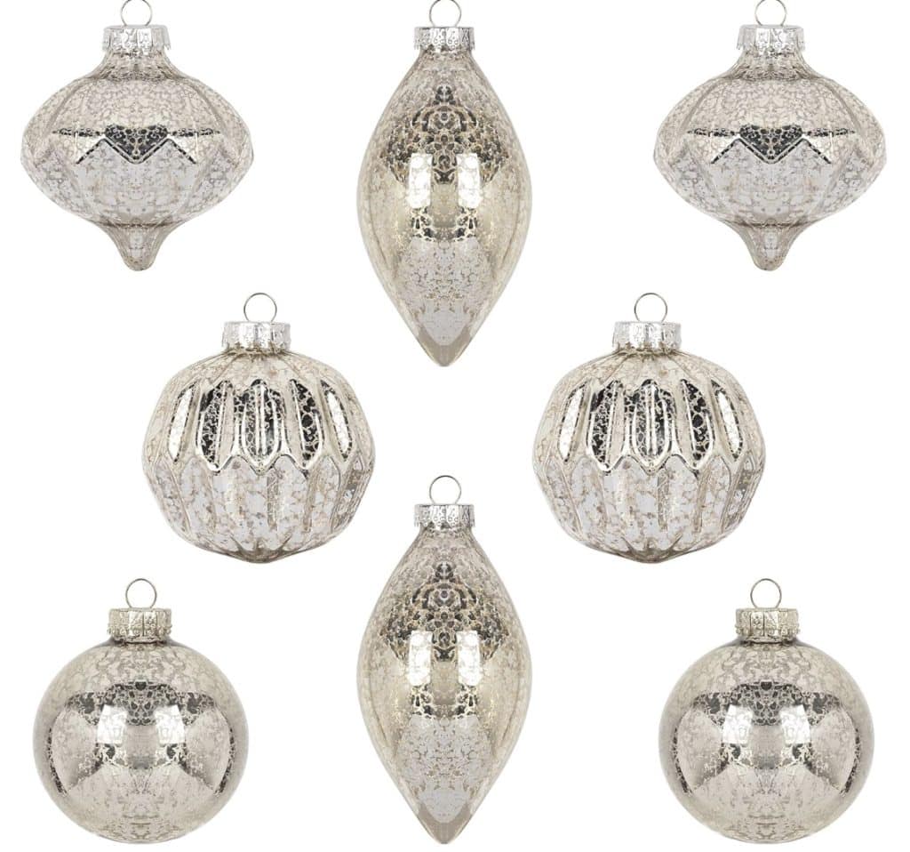 Seven silver Christmas ornaments in various shapes, including round, teardrop, and pointed designs with a reflective finish, mingle beautifully with an array of brown and gold Christmas tree decorations.